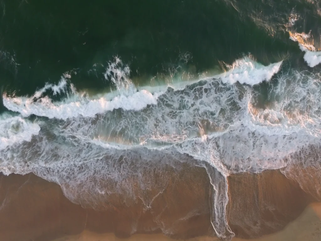 Waves washing on the sand - header image for the Practical Information page for Michael Conti